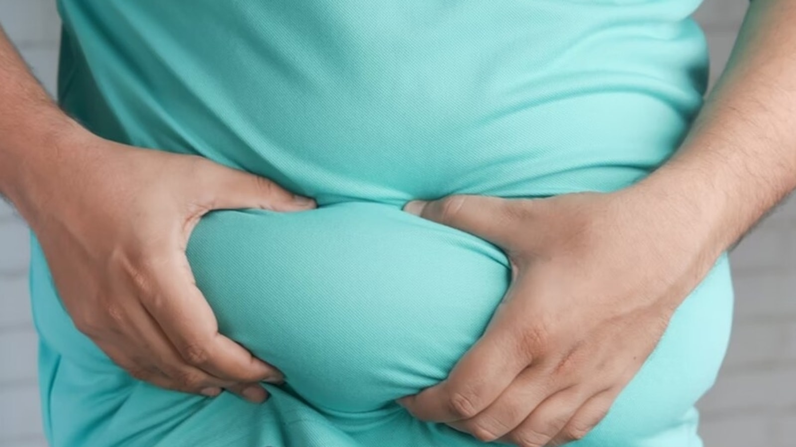 A person holding abdominal body fat through clothing